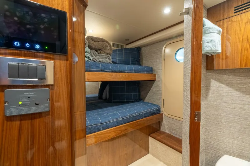 Slide: The Image of 2021 Viking 68 Enclosed Bridge Convertible cabin with bunk beds and wooden interior. - 32
