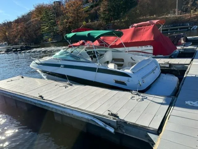 The Image of 2002 Crownline 215 CCR boat docked with green canopy, surrounded by autumn trees. - 0