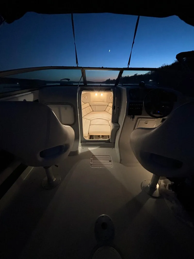 Slide: The Image of 2002 Crownline 215 CCR boat interior at dusk, illuminated cabin, serene evening sky. - 15