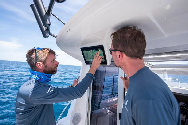 Slide: The Image of Two people using navigation equipment on a 2024 Beneteau Antares 8 Fishing boat. - 9