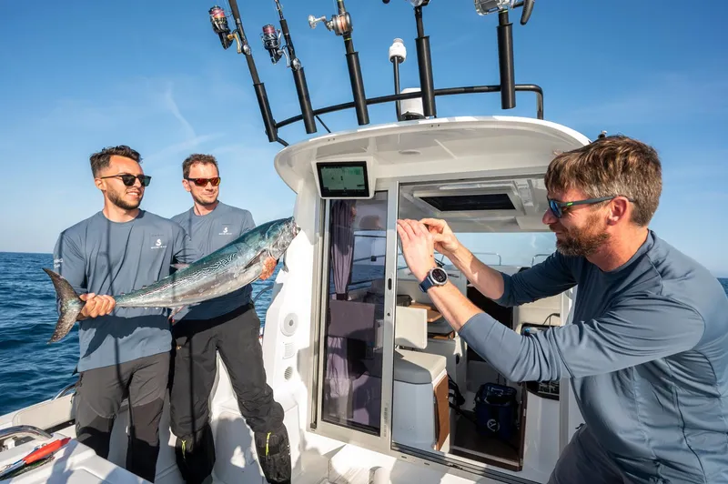 Slide: The Image of Men fishing on a 2024 Beneteau Antares 8, holding a large fish. - 10