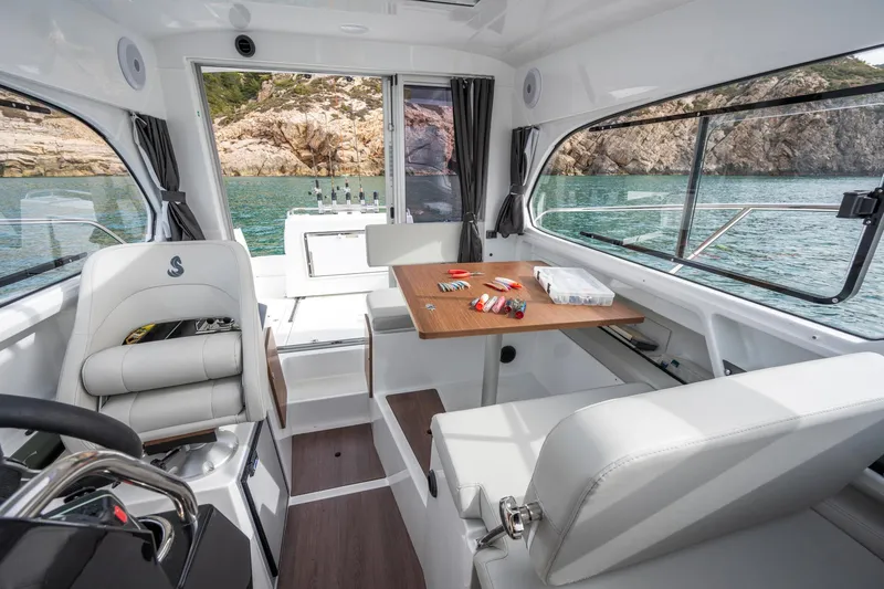 Slide: The Image of 2024 Beneteau Antares 8 Fishing boat interior with seating and table, overlooking scenic water. - 7