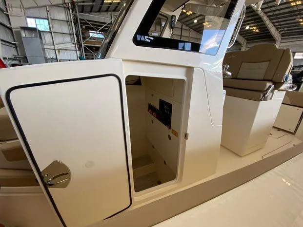 Slide: The Image of 2025 Scout 260 LXF boat interior with open cabin door in a warehouse. - 22