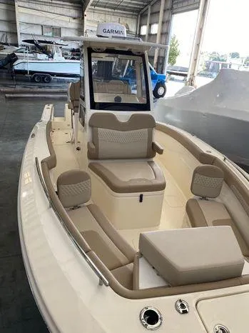 Slide: The Image of 2025 Scout 260 LXF boat interior with beige seating in a marina setting. - 6