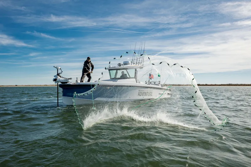 The Image of 2025 Axopar 29 CCX boat with fisherman casting net on open water. - 0