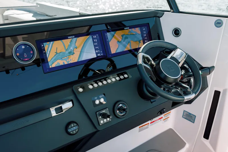 Slide: The Image of 2025 Axopar 29 CCX boat dashboard with dual navigation screens and steering wheel. - 12