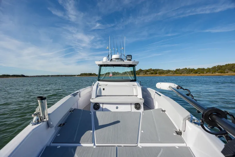 Slide: The Image of 2025 Axopar 29 CCX boat on calm water under clear blue sky. - 18