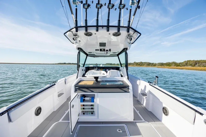 Slide: The Image of 2025 Axopar 29 CCX boat interior with fishing rod holders on a calm lake. - 19