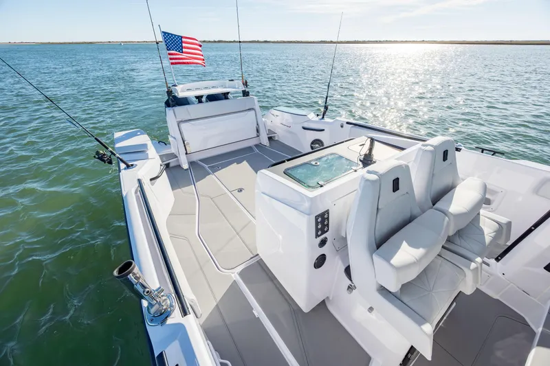 Slide: The Image of 2025 Axopar 29 CCX boat on water, featuring fishing rods and American flag. - 27