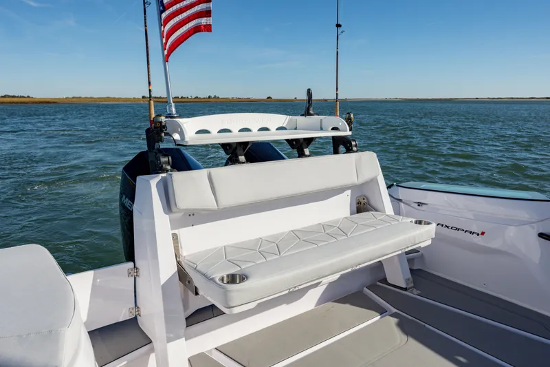 Slide: The Image of 2025 Axopar 29 CCX boat with seating, American flag, and ocean backdrop. - 28