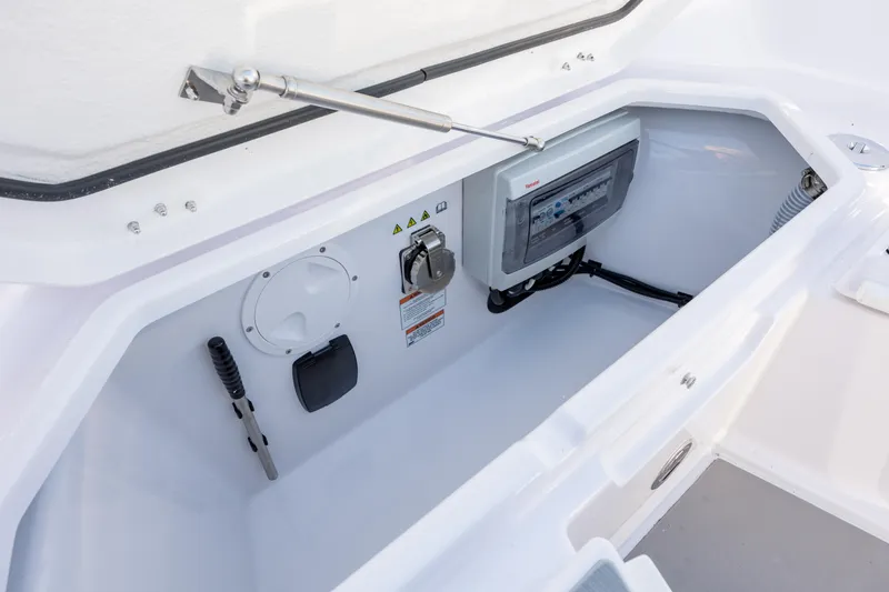 Slide: The Image of 2025 Axopar 29 CCX storage compartment with control panel and tools. - 30