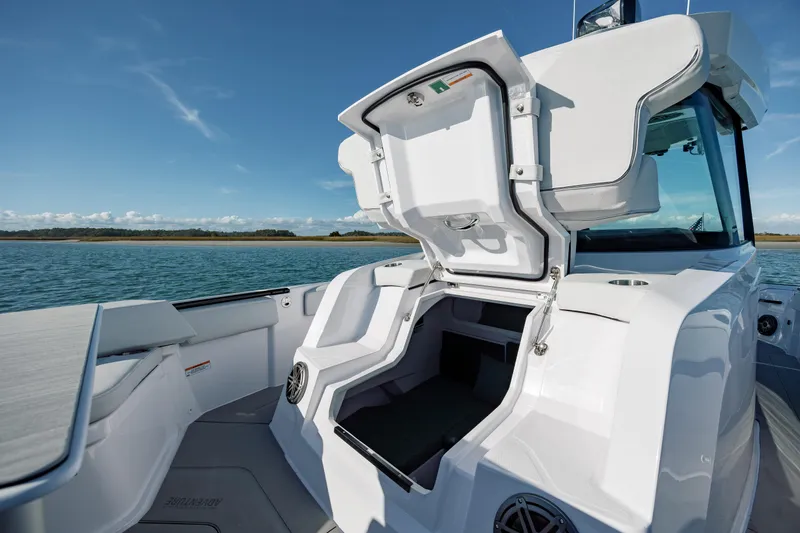 Slide: The Image of 2025 Axopar 29 CCX boat with open storage compartment on a sunny day. - 34