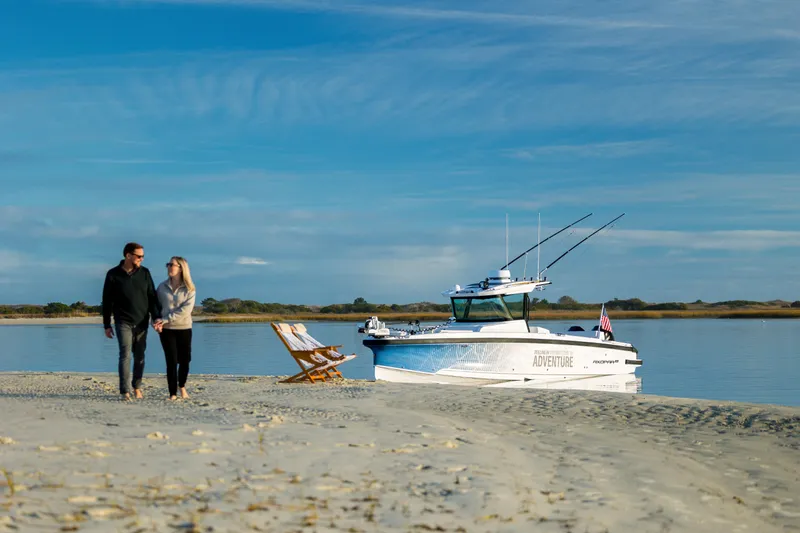 Slide: The Image of Couple walking on beach near 2025 Axopar 29 CCX boat, serene coastal scene. - 44