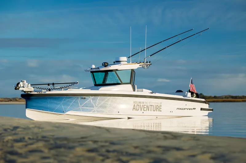 Slide: The Image of 2025 Axopar 29 CCX boat on calm water, featuring sleek design and fishing rods. - 46