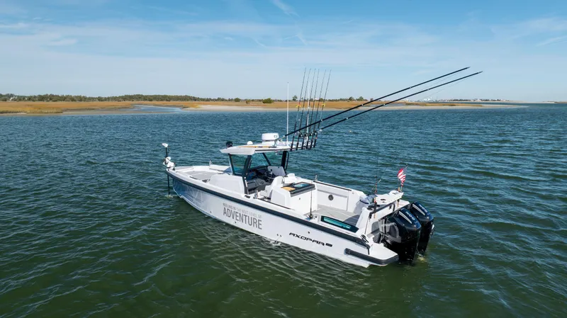 Slide: The Image of 2025 Axopar 29 CCX boat on water, equipped for fishing, with clear skies. - 6