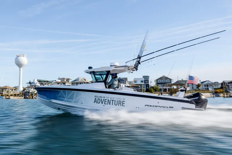 Slide: The Image of 2025 Axopar 29 CCX boat speeding on water near coastal town. - 8