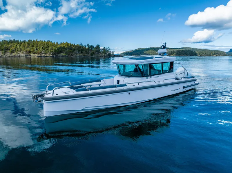 Slide: The Image of 2022 Axopar 28 boat cruising on a serene lake under a clear blue sky. - 11