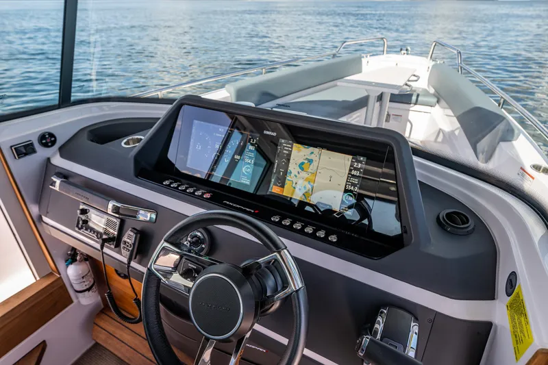 Slide: The Image of 2022 Axopar 28 boat dashboard with navigation display and steering wheel on open water. - 30
