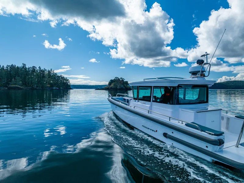 Slide: The Image of 2022 Axopar 28 boat cruising on a serene lake under a blue sky. - 5