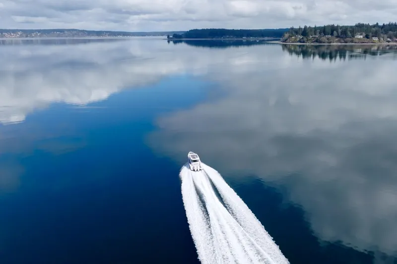 Slide: The Image of Axopar 37 XC 2021 cruising on a serene, reflective lake under cloudy skies. - 3