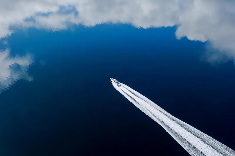 Slide: The Image of Axopar 37 XC 2021 boat cruising on calm blue water with cloud reflections. - 36