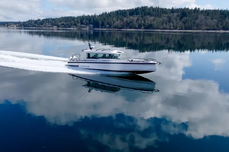 Slide: The Image of 2021 Axopar 37 XC cruising on calm, reflective water with forested shoreline. - 37