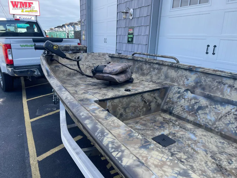 Slide: The Image of 2025 Excel 1751 River Warrior boat with camouflage design, parked near a garage. - 9
