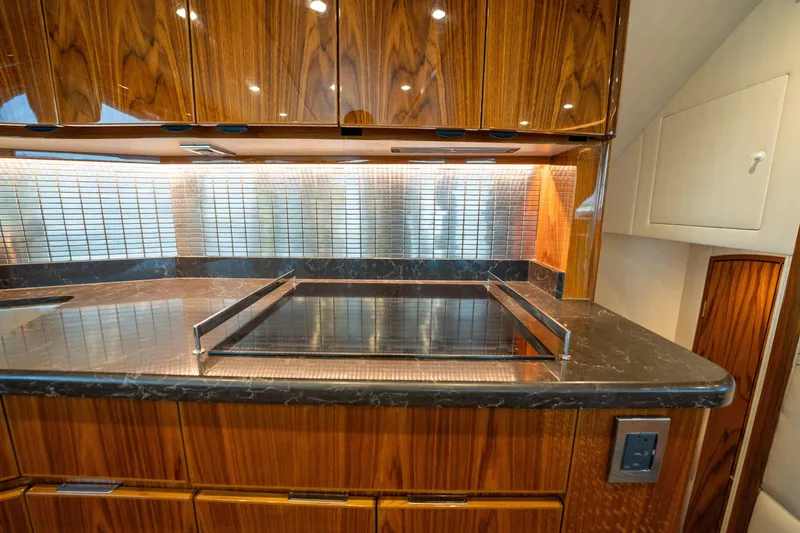 Slide: The Image of Luxurious kitchen interior of 2022 Viking 54 Convertible yacht with sleek wood cabinetry. - 17