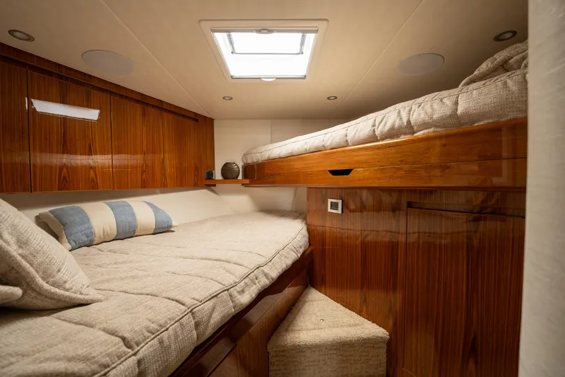 Slide: The Image of Cozy cabin interior of 2022 Viking 54 Convertible yacht with wooden finishes and twin beds. - 23
