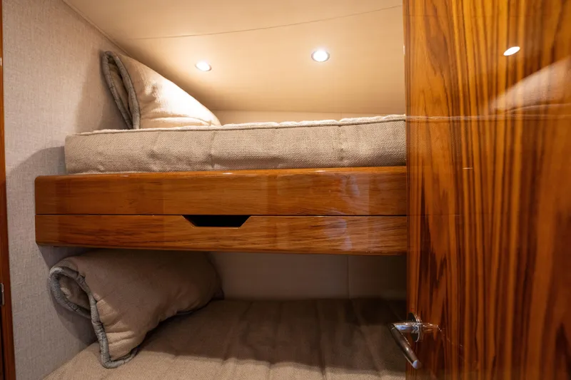 Slide: The Image of 2022 Viking 54 Convertible yacht cabin with wooden bunk beds and cozy lighting. - 28