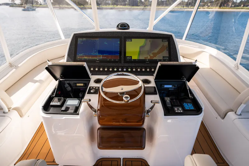 Slide: The Image of 2022 Viking 54 Convertible yacht helm with open compartments, overlooking serene water. - 36