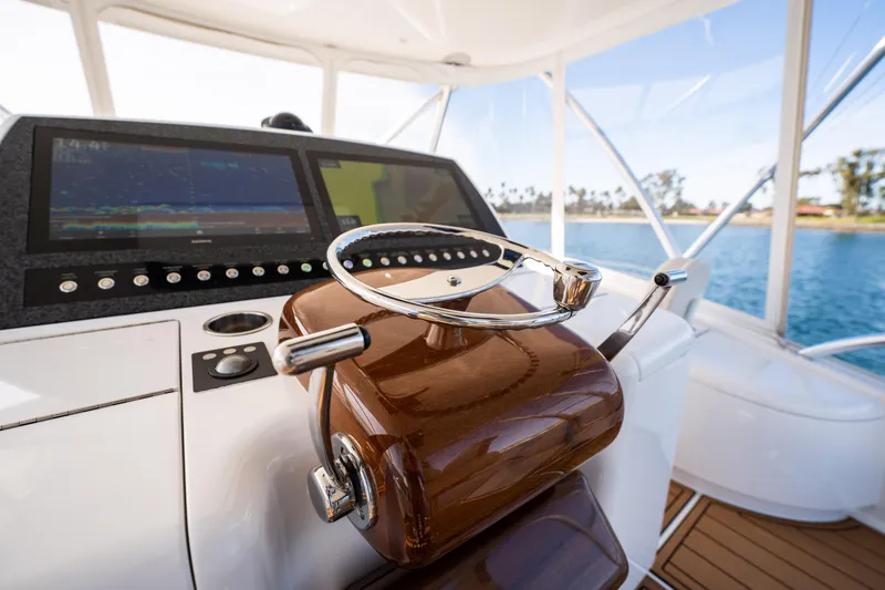 Slide: The Image of 2022 Viking 54 Convertible yacht bow on calm water, clear sky, and distant shoreline. - 44