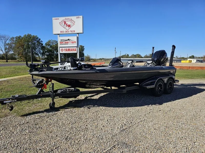 The Image of 2025 Skeeter FXR21L bass boat on trailer, parked outdoors under clear blue sky. - 1