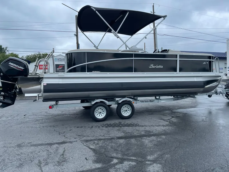Slide: The Image of 2024 Barletta ARIA 22QC pontoon boat on trailer, black exterior, overcast day. - 10