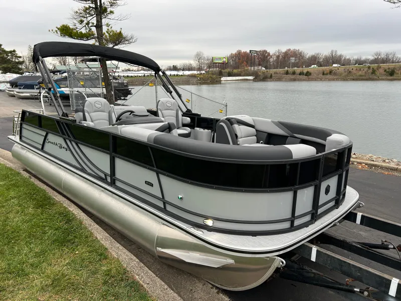 Slide: The Image of 2025 South Bay S224 UL pontoon boat docked by a serene lakeside. - 3