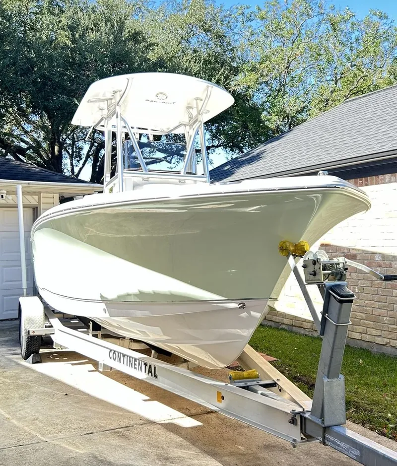 The Image of 2022 Sea Hunt Ultra 234 boat on trailer, parked in driveway, under clear sky. - 0