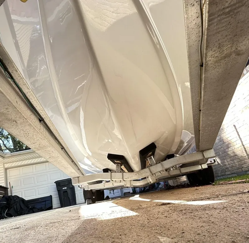 Slide: The Image of 2022 Sea Hunt Ultra 234 boat on trailer, viewed from below in a driveway setting. - 10