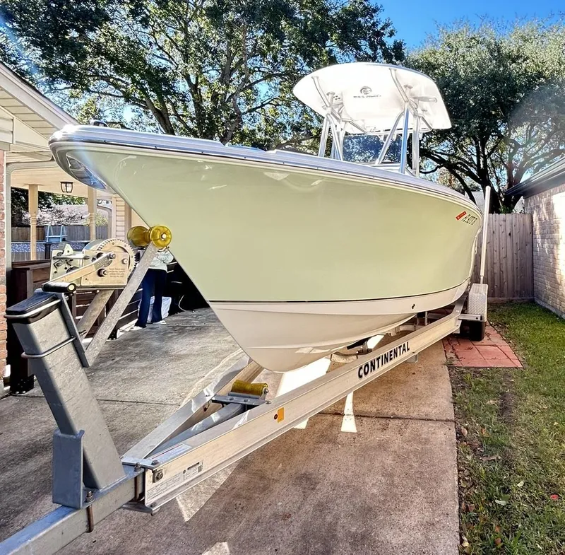 Slide: The Image of 2022 Sea Hunt Ultra 234 boat on trailer, parked in driveway, surrounded by trees. - 11