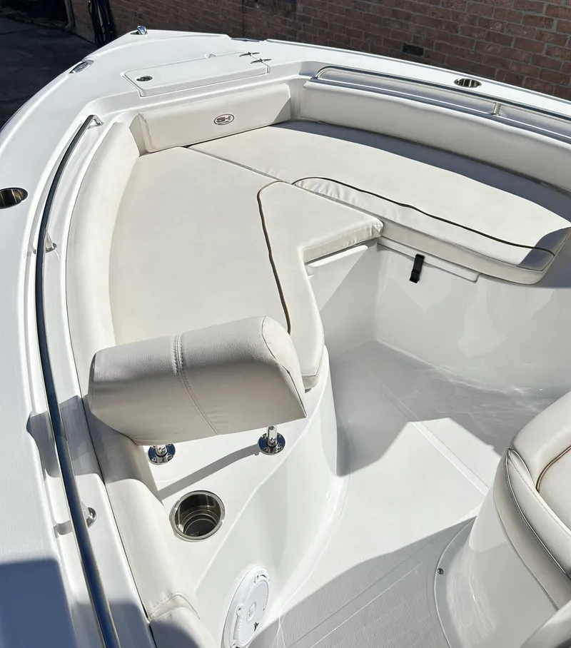 Slide: The Image of 2022 Sea Hunt Ultra 234 boat interior with white cushioned seating and cup holders. - 2
