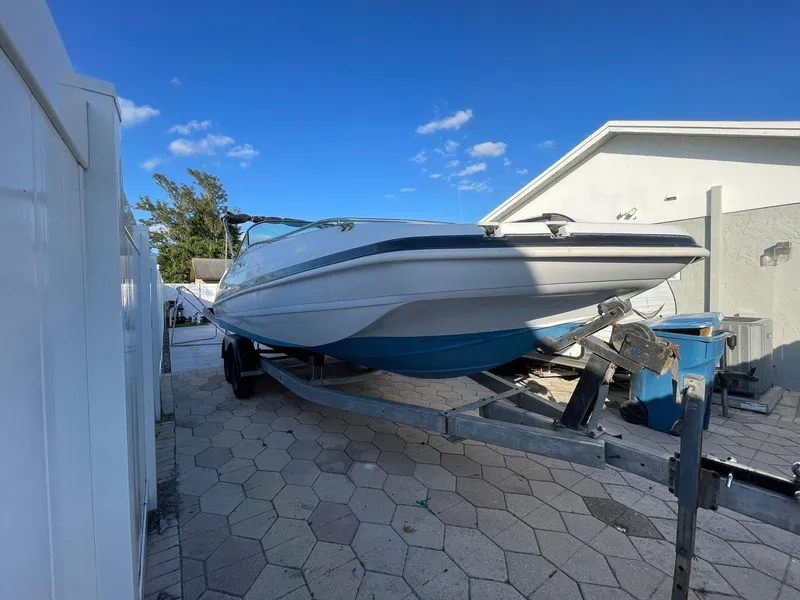 Slide: The Image of 2001 Hurricane 232 OB boat on trailer, parked in driveway under clear blue sky. - 0