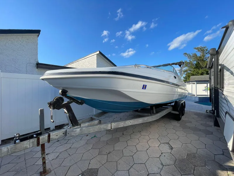 Slide: The Image of 2001 Hurricane 232 OB boat on trailer, parked in driveway under clear blue sky. - 2