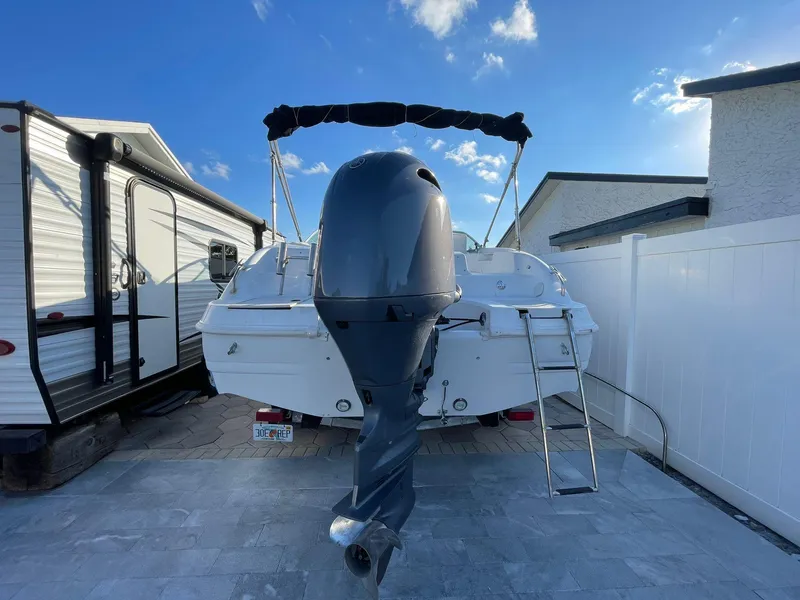 Slide: The Image of 2001 Hurricane 232 OB boat with outboard motor, parked beside RV and house. - 4