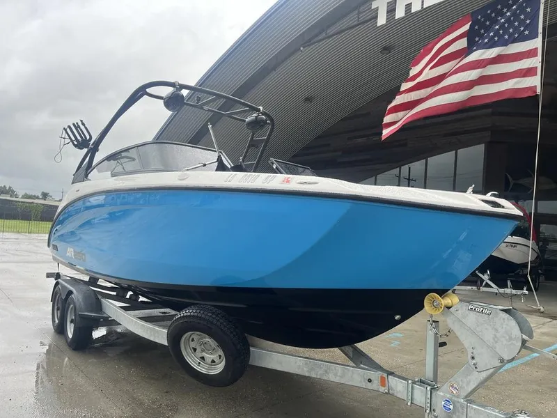 Slide: The Image of 2023 Yamaha AR250 boat on trailer, blue hull, American flag in background. - 12