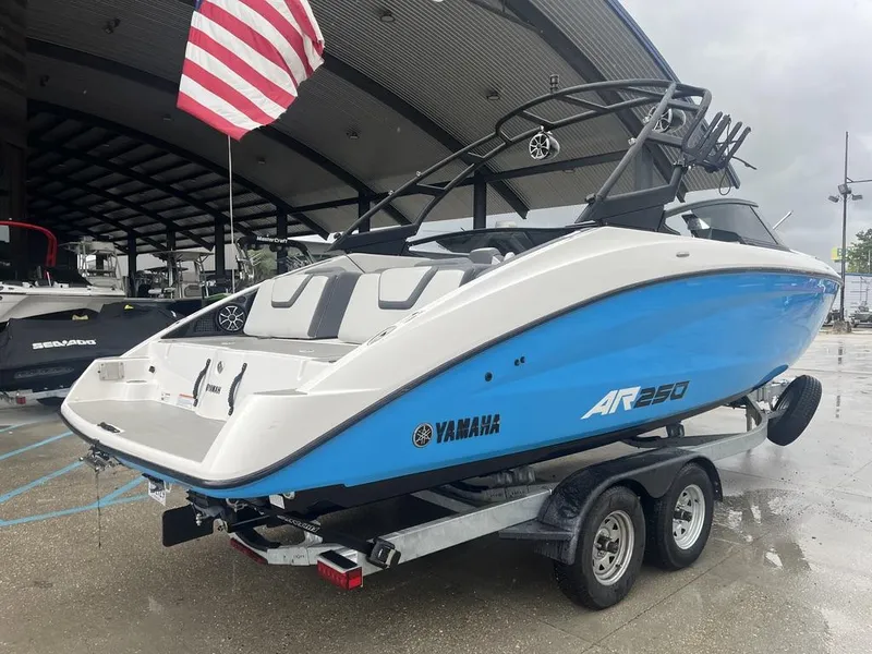 Slide: The Image of 2023 Yamaha AR250 boat on trailer, under shelter, with American flag. - 2