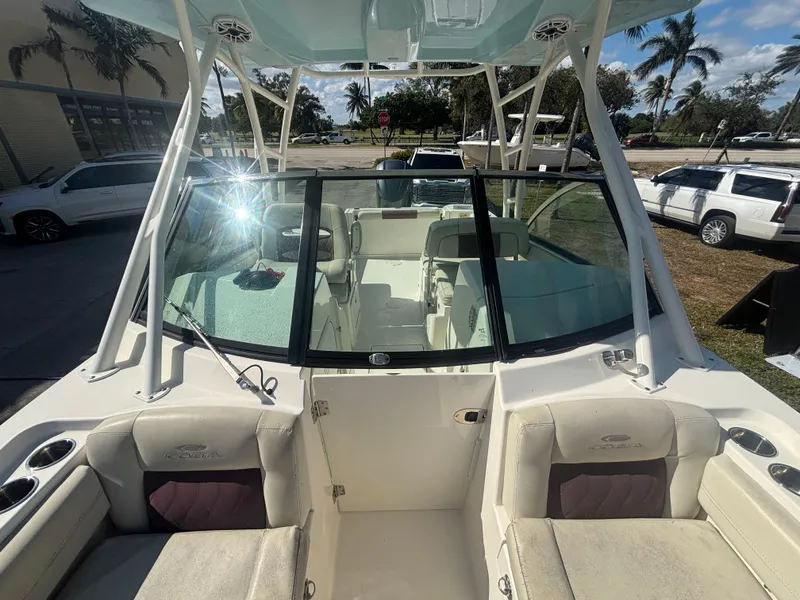 Slide: The Image of 2021 Cobia 240 Dual Console boat interior with seating and windshield, parked outdoors. - 14