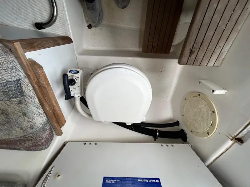 Slide: The Image of 1996 Robalo 2440 Walkaround boat interior with marine toilet and wooden accents. - 18