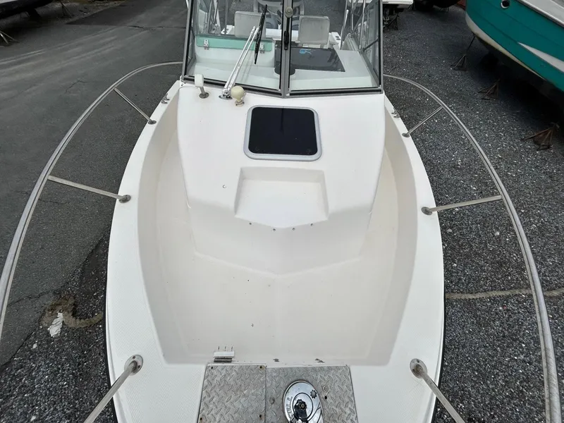 Slide: The Image of 1996 Robalo 2440 Walkaround boat, white deck, windshield, and railing, parked on gravel. - 21