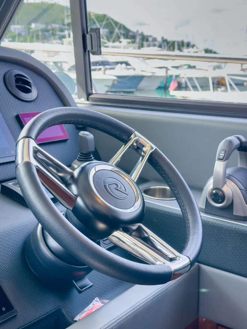 Slide: The Image of 2024 Riviera 465 SUV steering wheel and controls in a marina setting. - 10