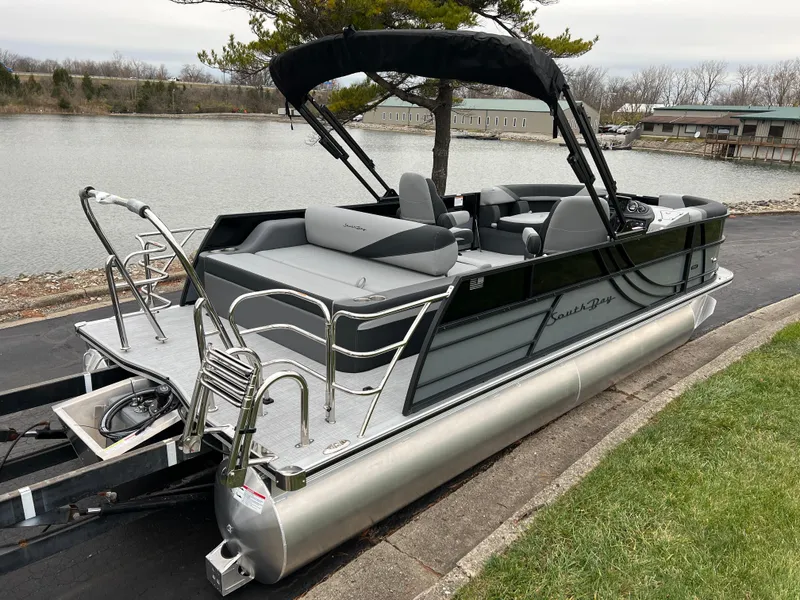 Slide: The Image of 2025 South Bay S222 UL pontoon boat docked by a serene lakeside. - 5