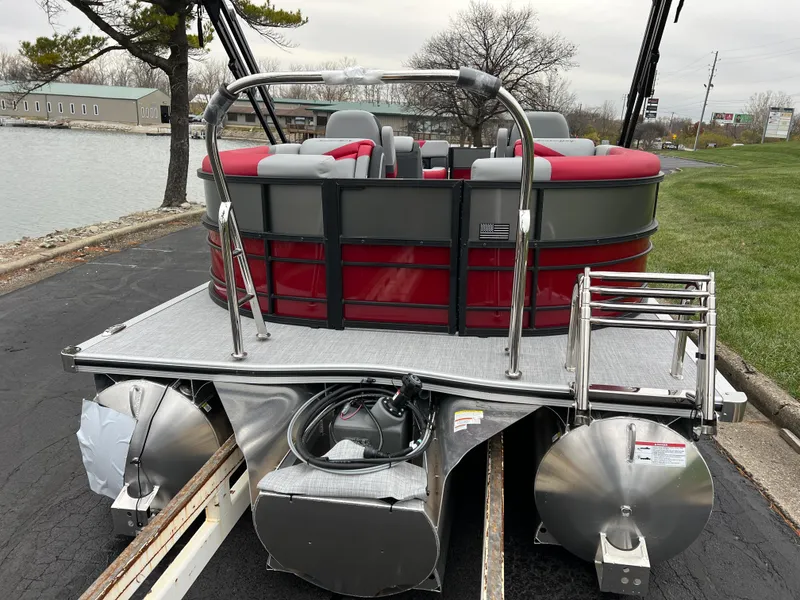 Slide: The Image of 2025 South Bay S222 RS Tri 3.0 pontoon boat with red seating, docked by a lake. - 6